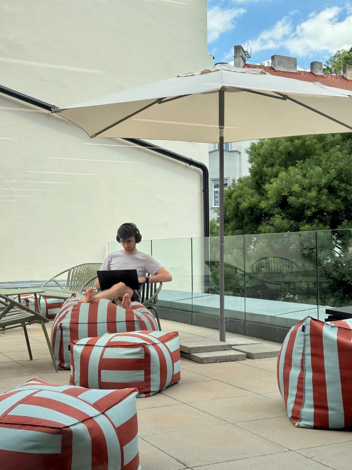 A teammate working on a laptop under the umbrella on the rooftop terrace